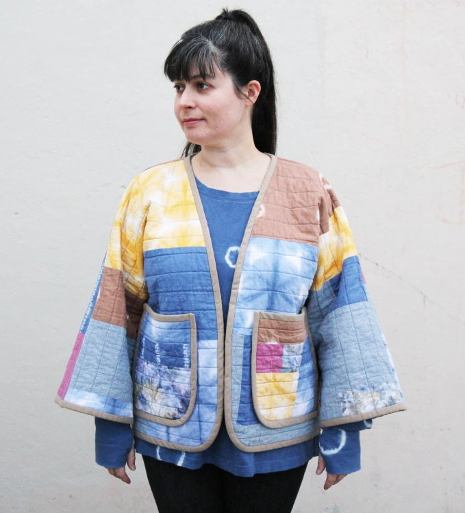 woman wearing colorful quilted patchwork jacket over blue shirt