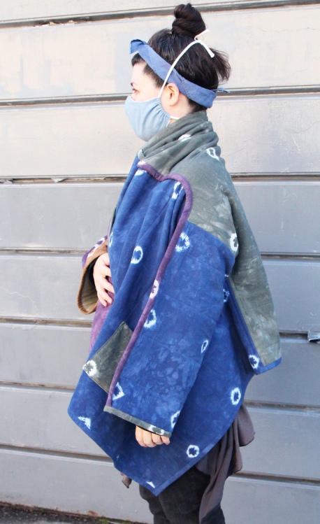 side view of woman wearing blue and green quilt coat on city sidewalk
