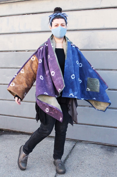 woman standing on sidewalk wearing colorful hand dyed quilt coat and face mask