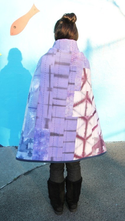 back view of woman with colorful patchwork quilt wrapped around herself