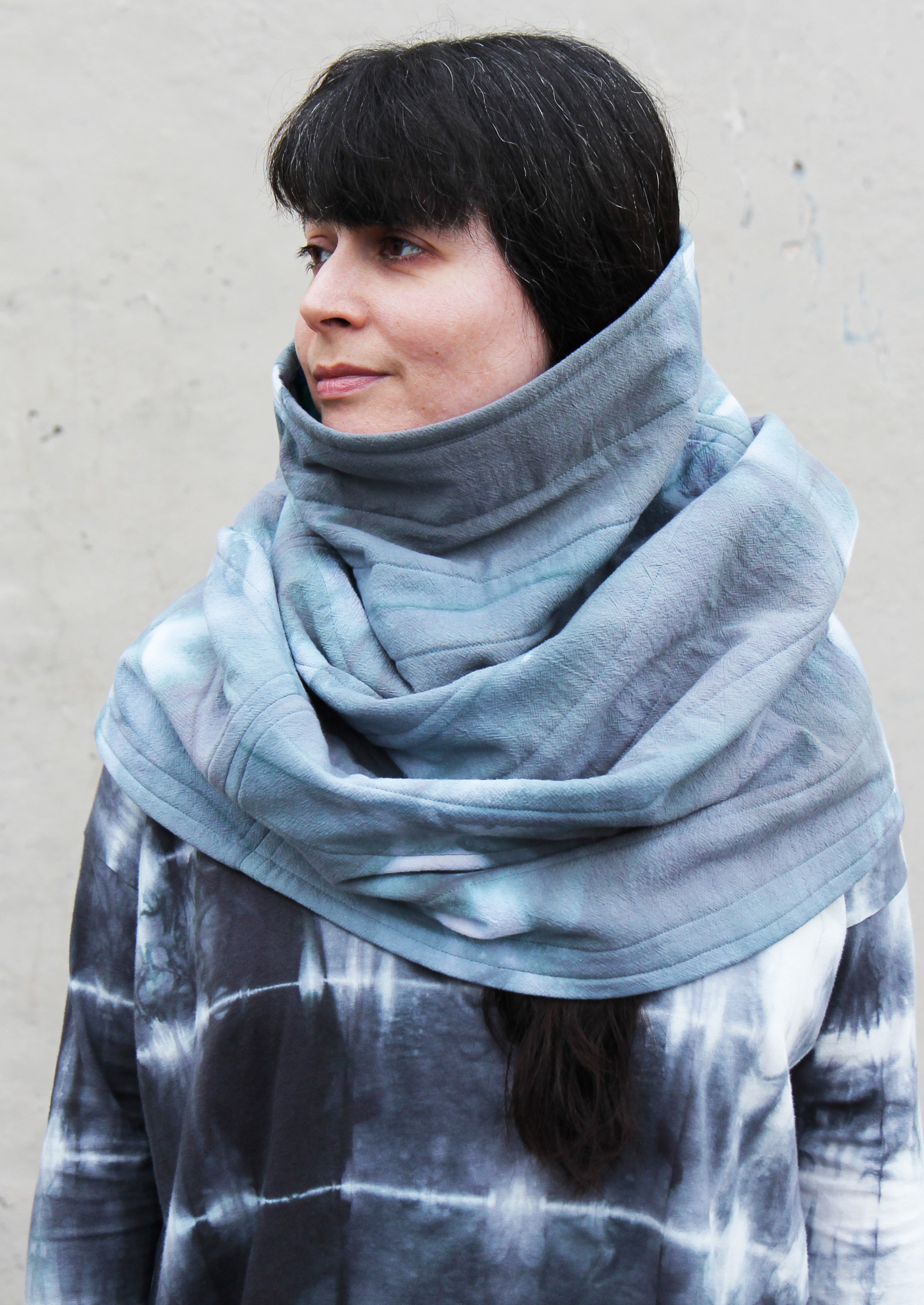 woman with black hair wearing a green quilted cowl