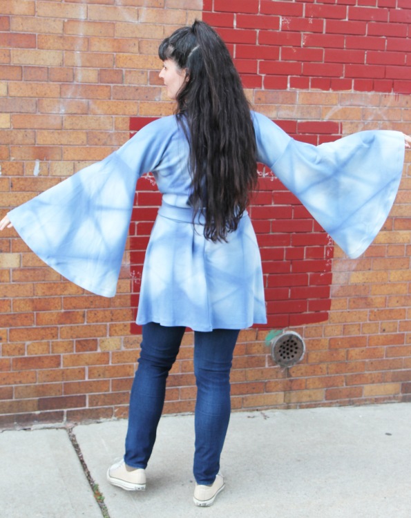 back view of woman with long hair wearing blue top with big bell sleeves