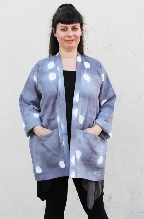 woman wearing gray linen jacket with white circle pattern and large patch pockets over black top and pants